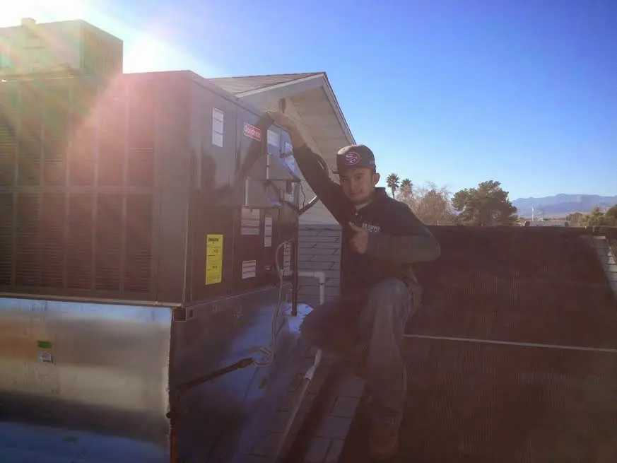HVAC technician performing Air Duct Repair on a rooftop unit in Woodland Park