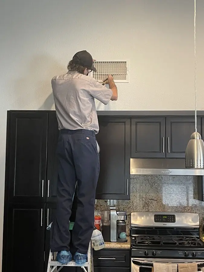 Technician inspecting an air vent during HVAC service in Woodland Park